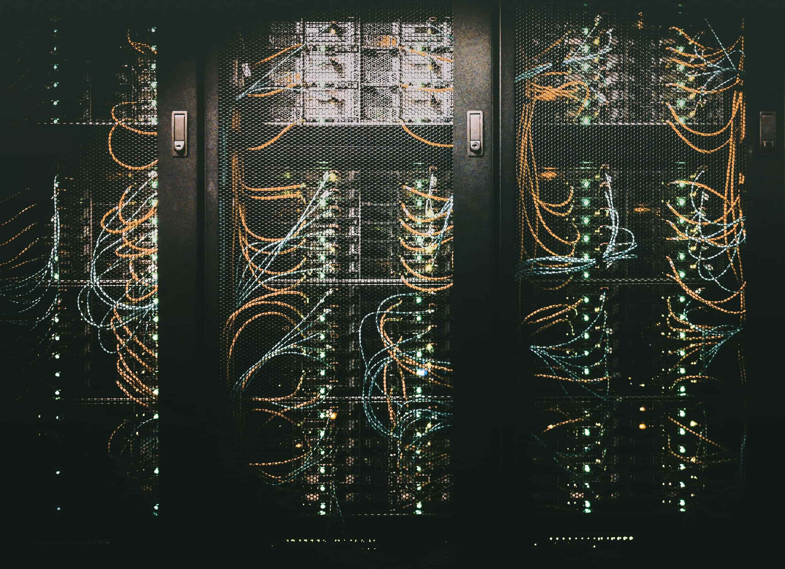 KI-Infrastruktur: Server-Racks mit leuchtenden Kabeln in einem Rechenzentrum zur Debatte um KI-Rechenleistung.