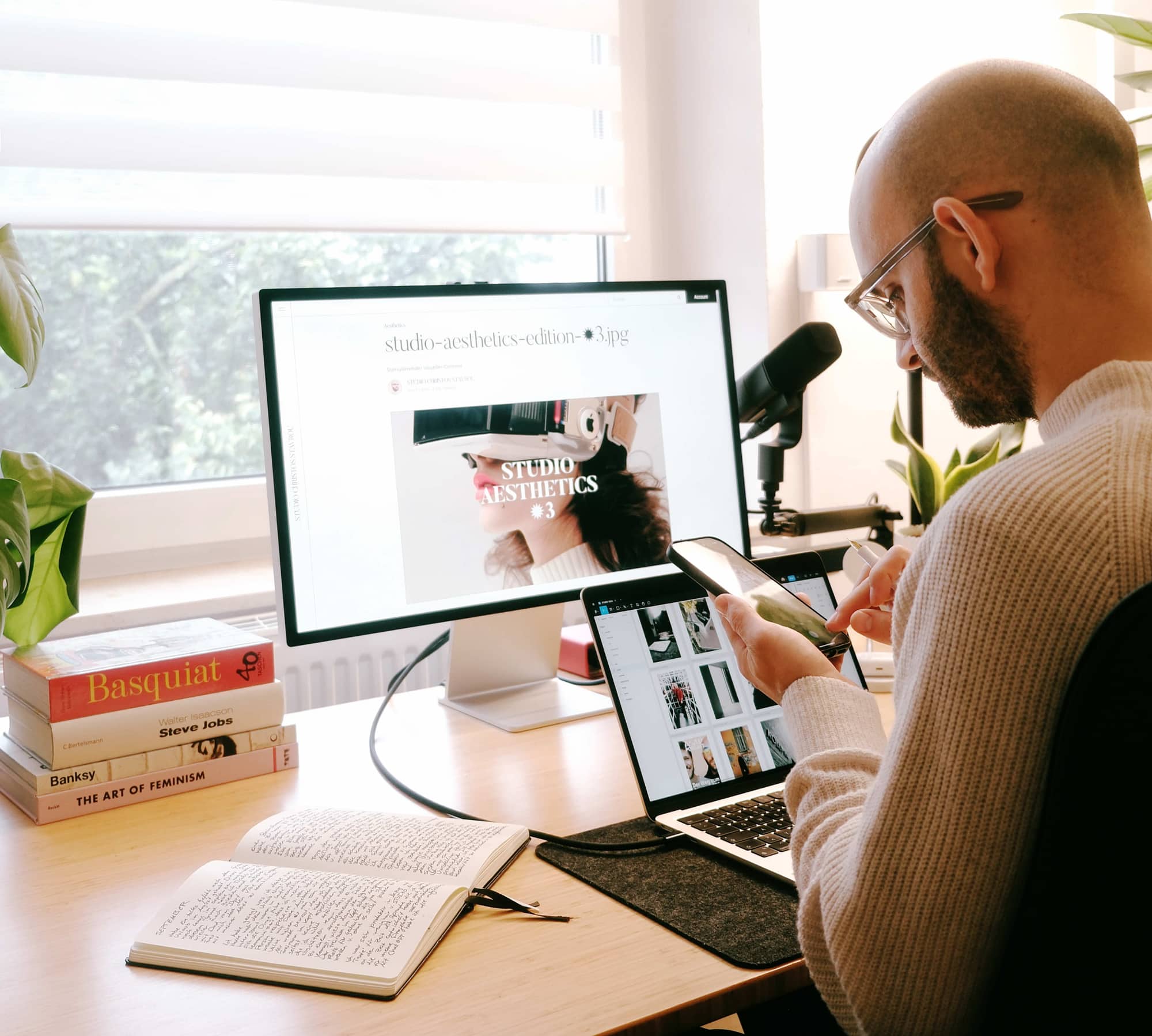 Mann arbeitet mit Monitor, Laptop, Smartphone und Notizbuch, Künstliche Intelligenz im Arbeitsalltag