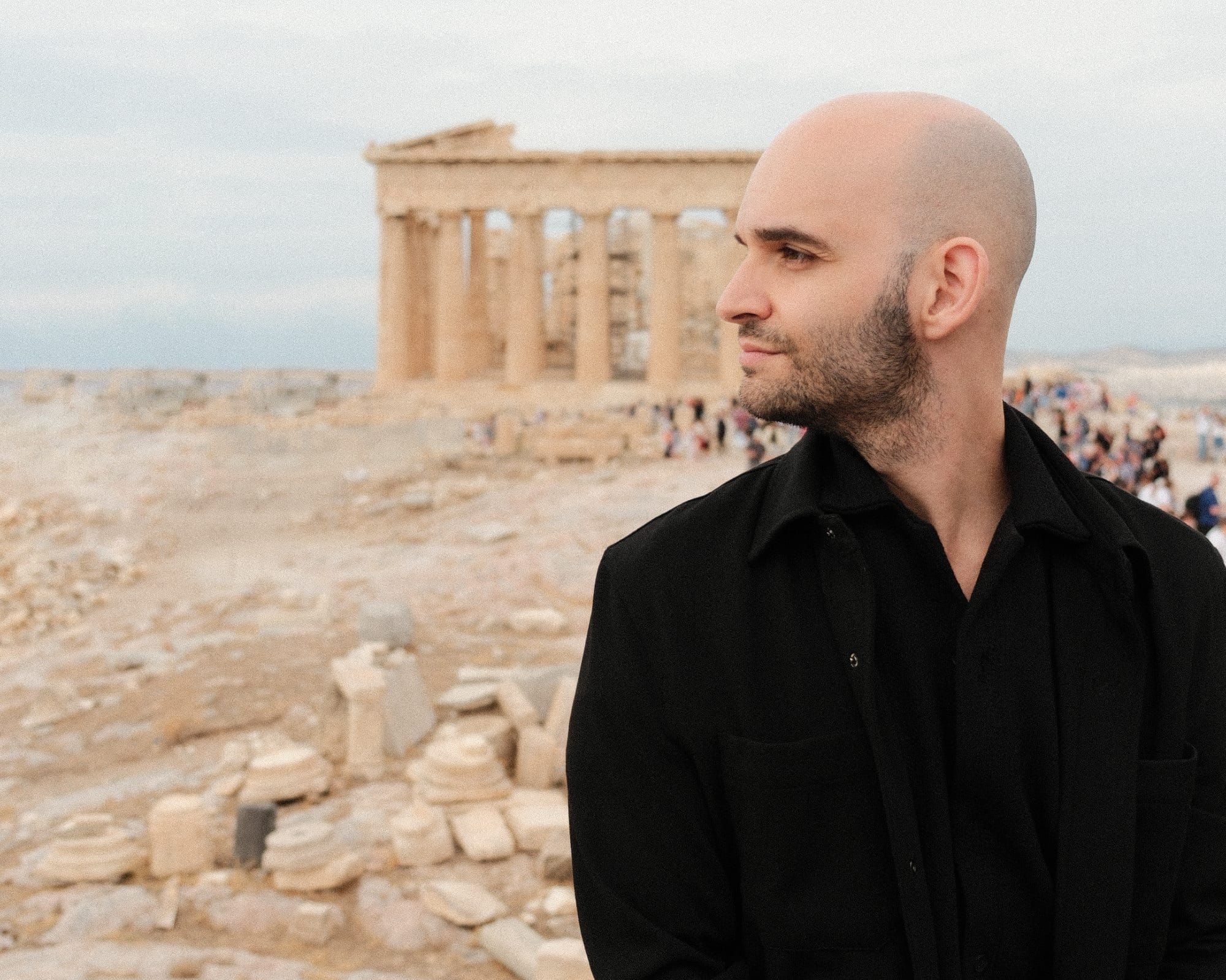 Christos Stavrou, KI-Berater aus Köln, im Profil vor der Akropolis in Athen. Schwarzes Hemd, Blick zur Seite. Gründer von Studio Christos.