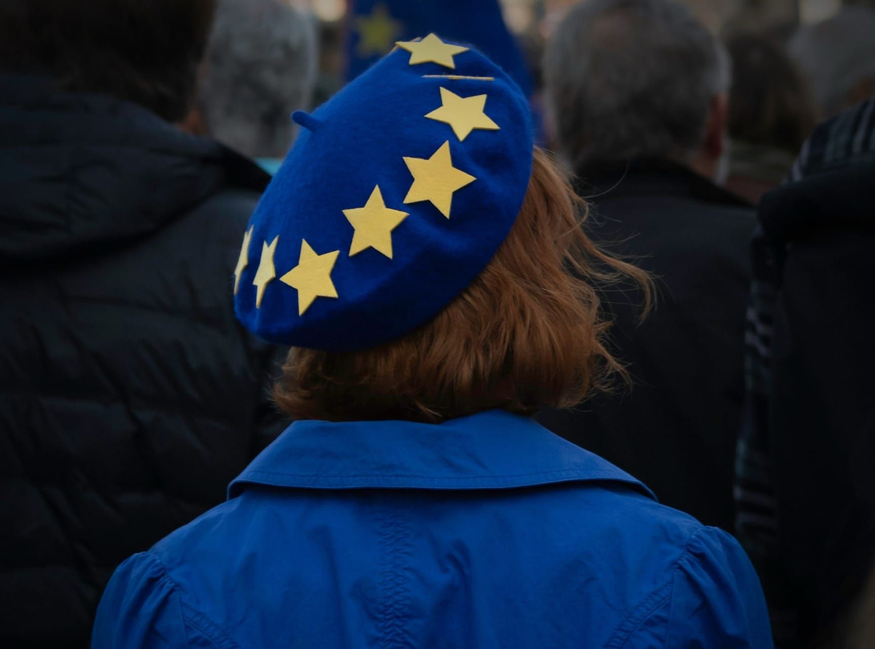 EU-KI-Debatte: Person von hinten mit blauem EU-Barett mit gelben Sternen zur europaeischen KI-Souveraenitaet.