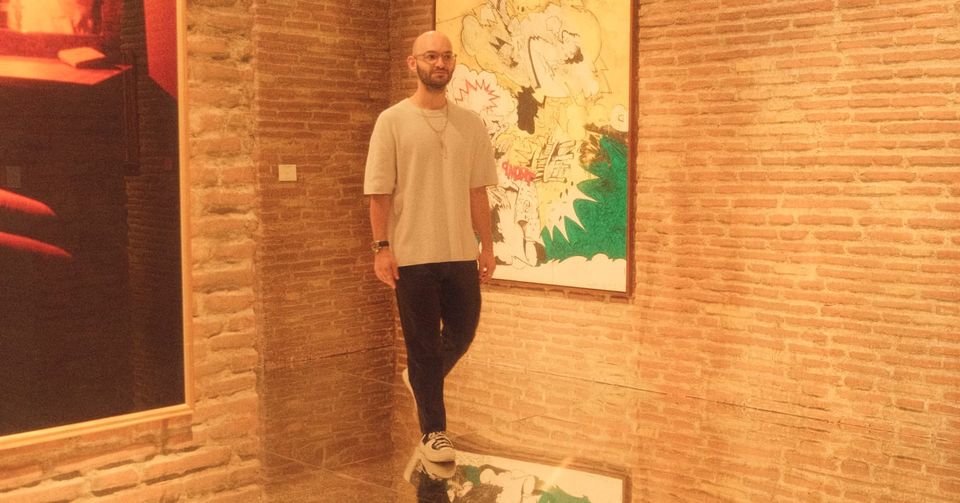 Christos Stavrou steht in einer Galerie und reflektiert den Wandel vom Spezialisten zum Generalisten. Thema von KI ✺ Kreative Intelligenz