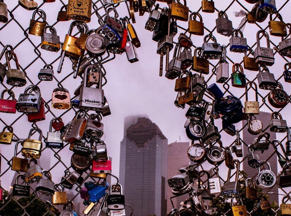 Viele Vorhängeschlösser an einem Zaun vor einem nebligen Hochhaus als Symbol für die Sperrung der Fabel 5 KI.