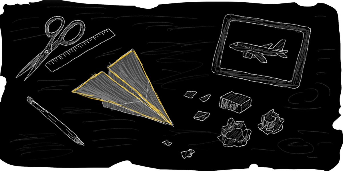 A desk with a paper airplane, and tools for creating the airplane