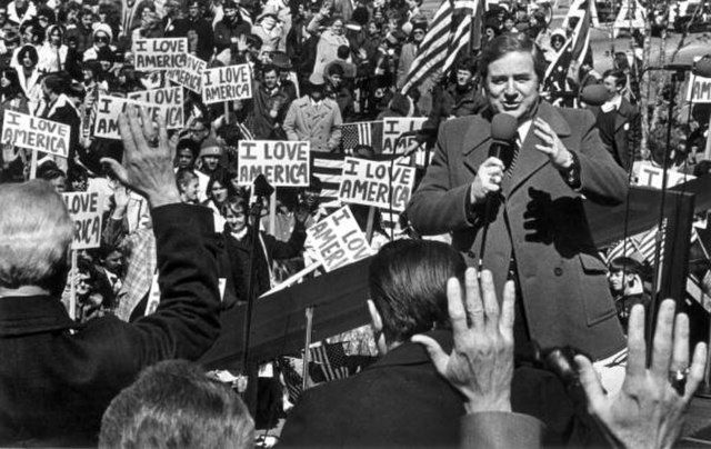Jerry Falwell at a rally, "I Love America" signs in the background