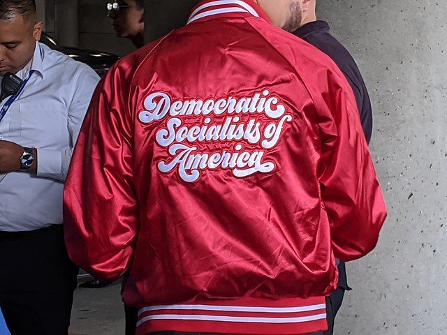 A man wearing a letterman-style red DSA jacket at a 2020 Bernie Sanders rally. 