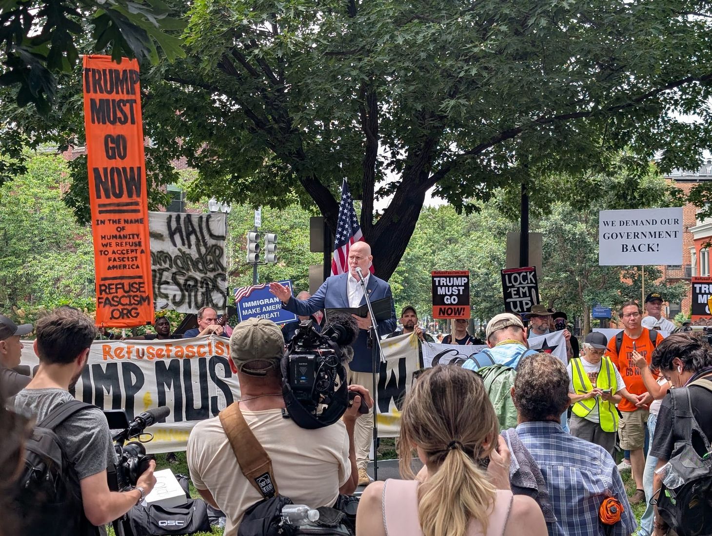 Activist Jim Keady speaking to Refuse Fascism's demonstrators in front of signs reading Trump Must Go Now.