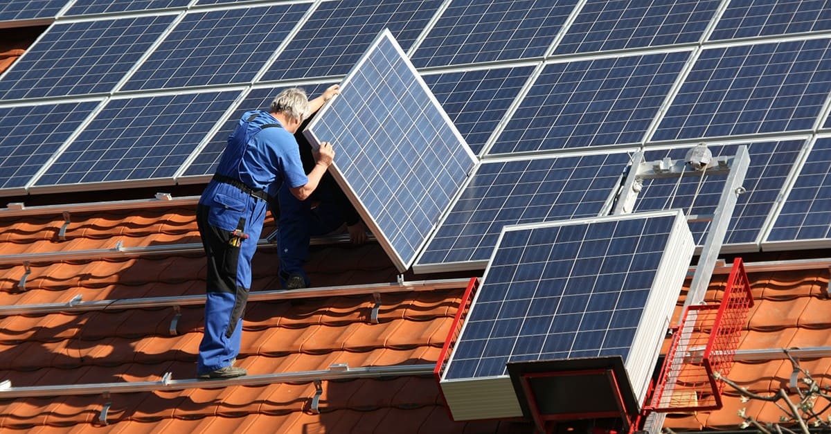 Técnico a instalar painéis solares no terraço do telhado de um vizinho