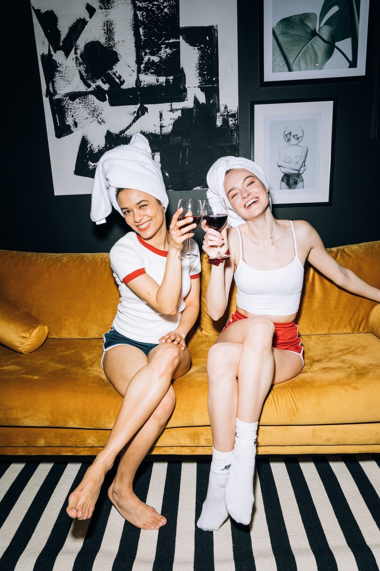 Dos chicas sonrientes brindan sentadas en el sofá de su casa