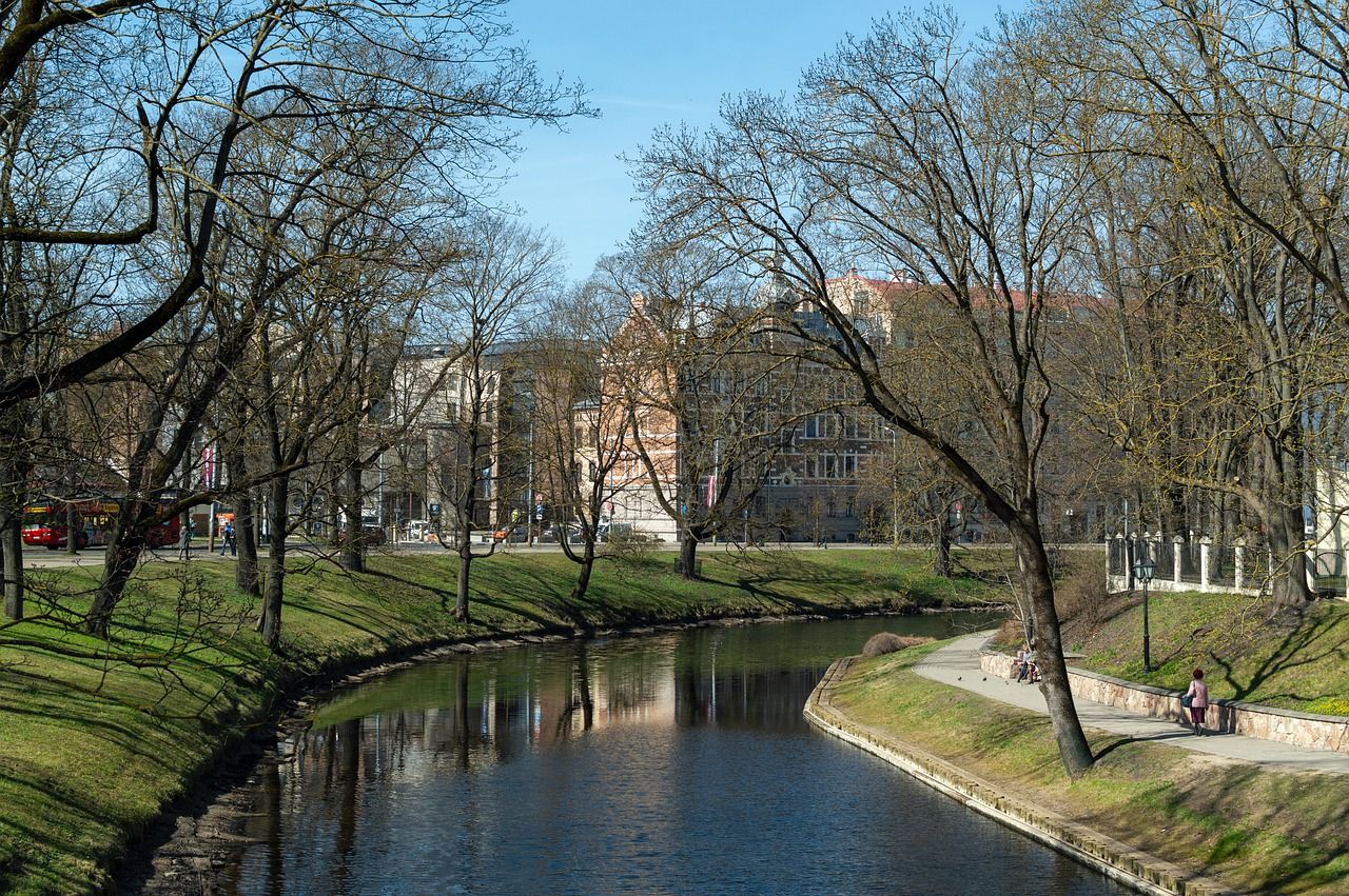 Parco Kronvalda attraversato da un ruscello con edifici sullo sfondo