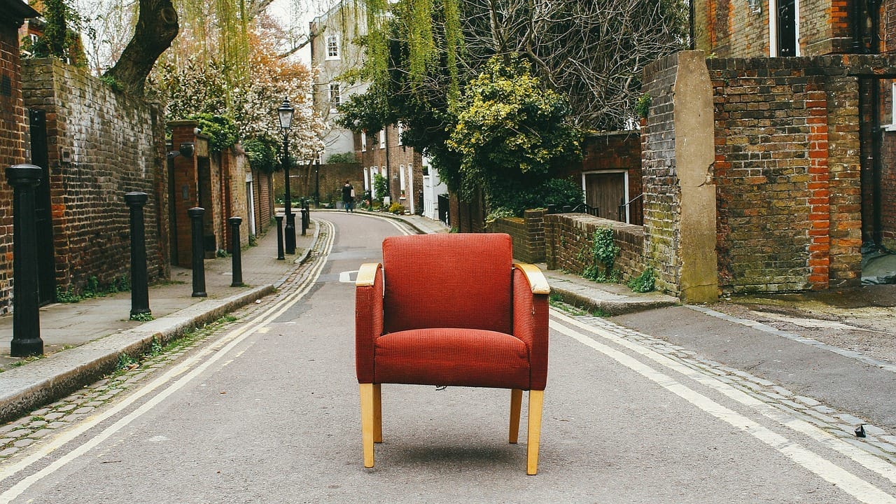 Red armchair in the middle of a street with brick walls