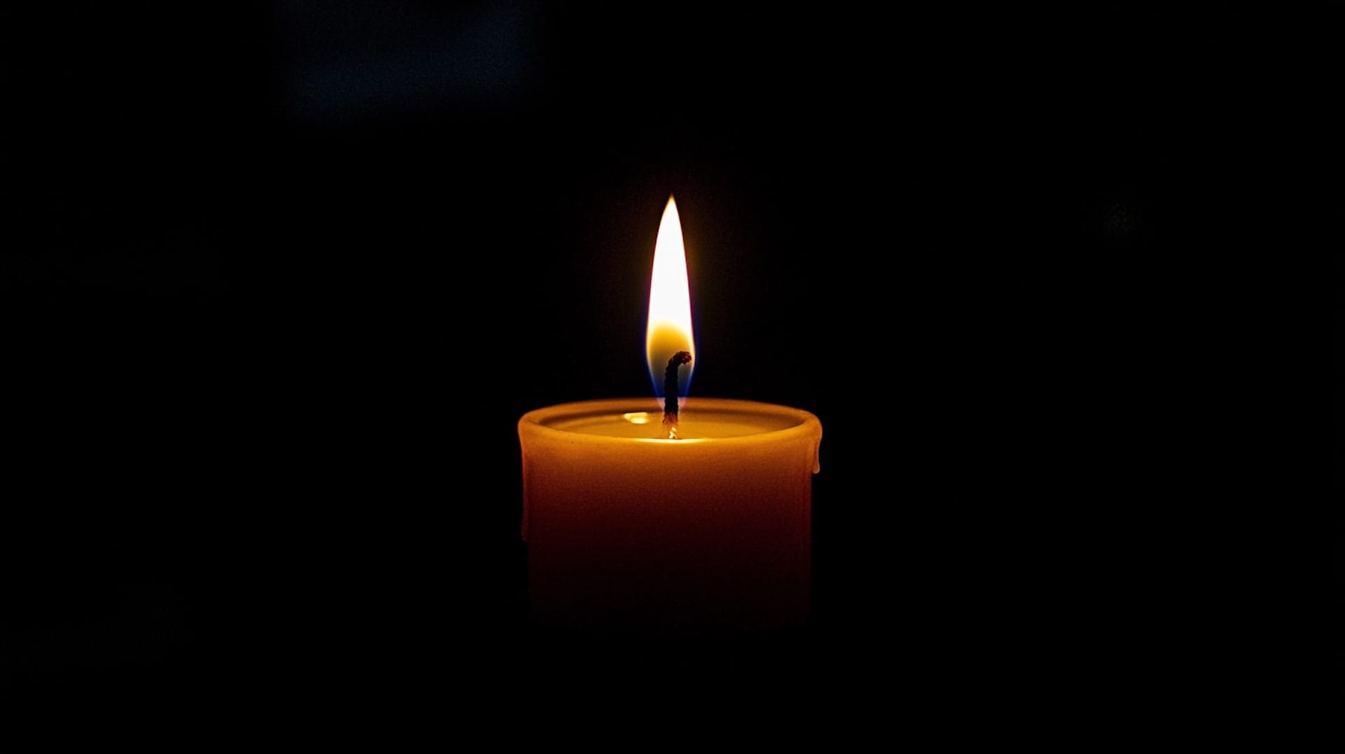 A candle with a still flame on a black background