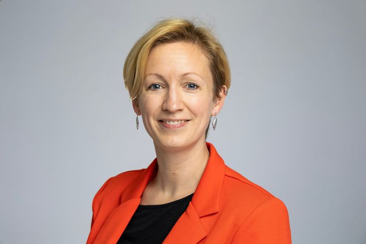 a professional head and shoulders shot of Sarah Kerr, Energy Systems Lead from Oxfordshire county council. She has short blond hair, with an orange jacket over a black top