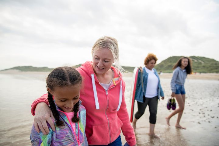 Women walking with children along a beach.
