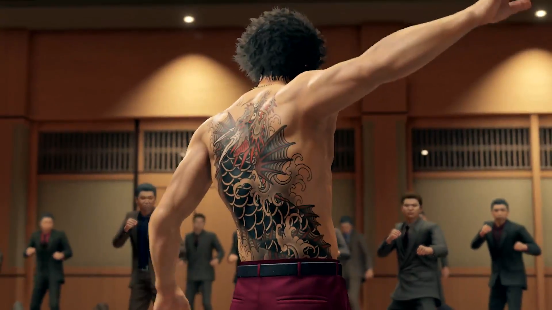 "A Yakuza: Like a Dragon screenshot of Ichiban Kasuga ripping off his jacket, revealing the dragonfish tattoo on his back. There are people ready to fight standing before him."