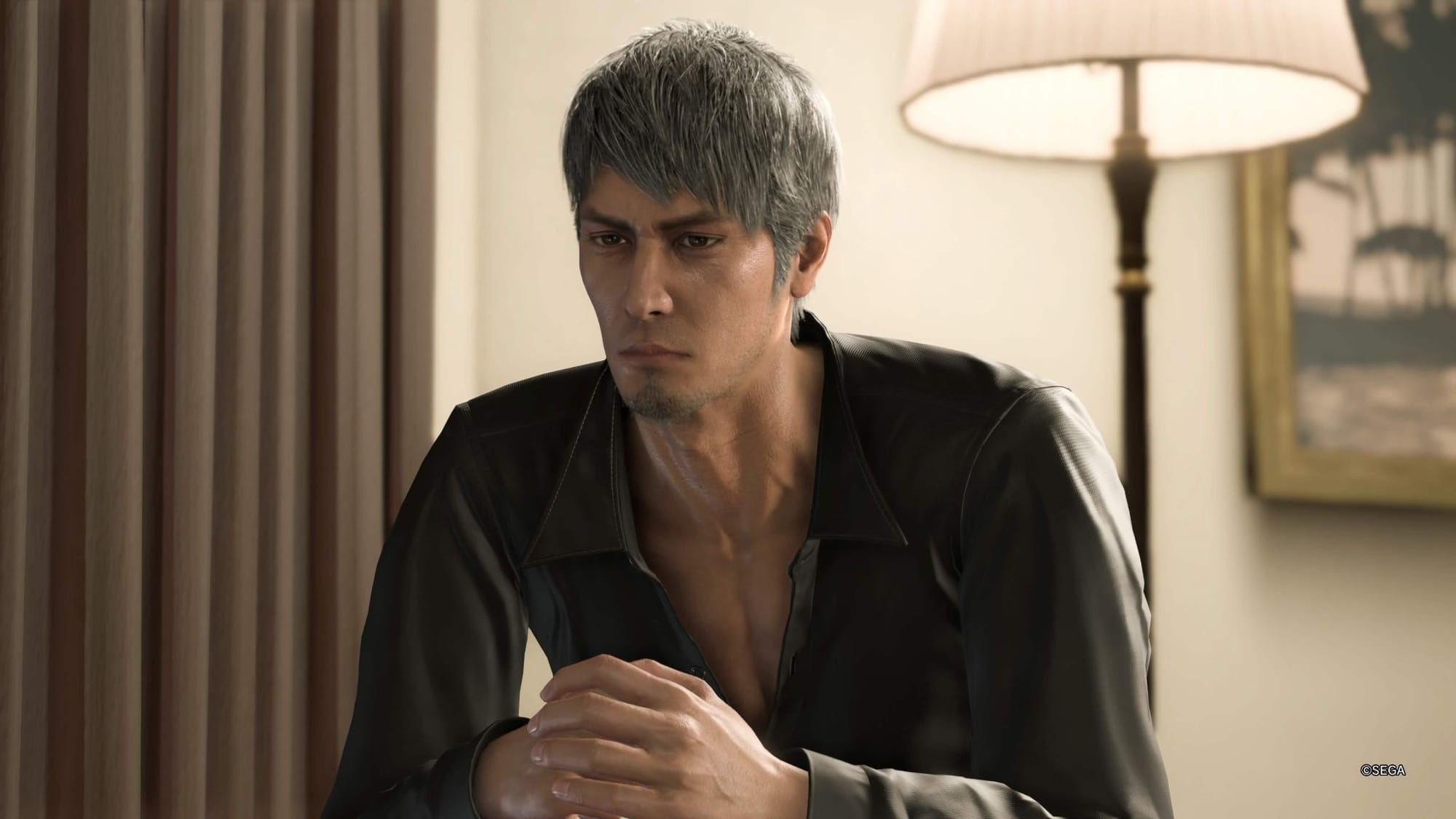 "A Like a Dragon: Infinite Wealth screenshot of Kazuma Kiryu sitting with his hands folded, looking solemn."