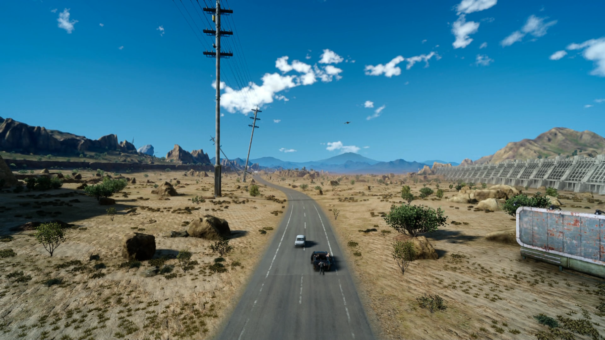 A road opens to clear blue skies. Two cars on the move.