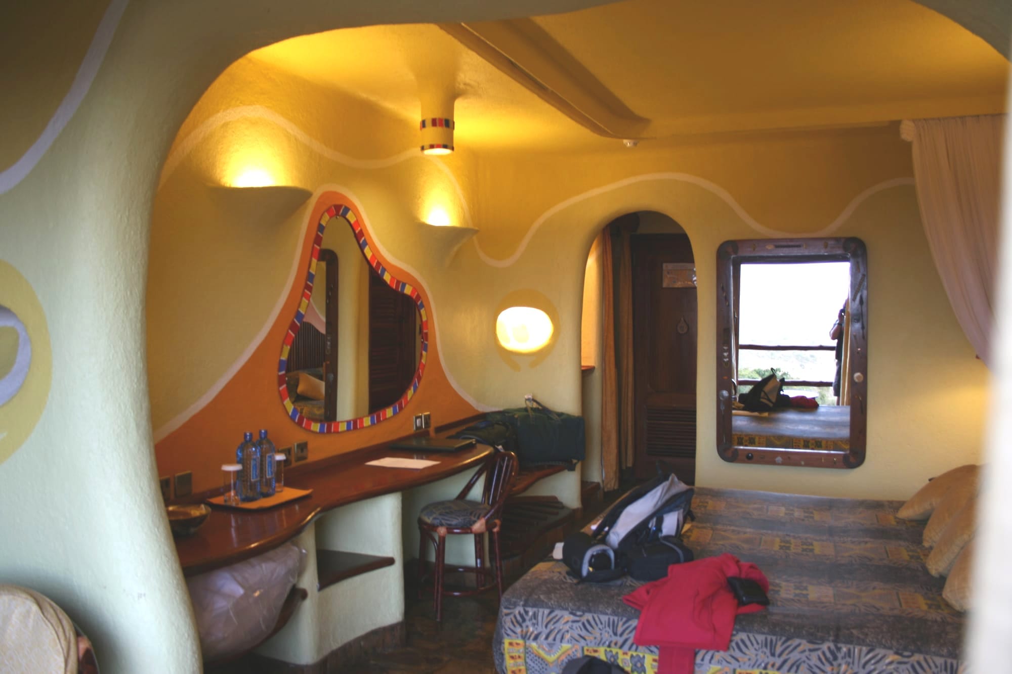 A themed hotel room with curved cave-like walls and mosaic-framed mirro
