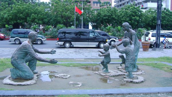 A scultputre of a father in one knee greeting his family with children running towards and mother all with outstretched arms.