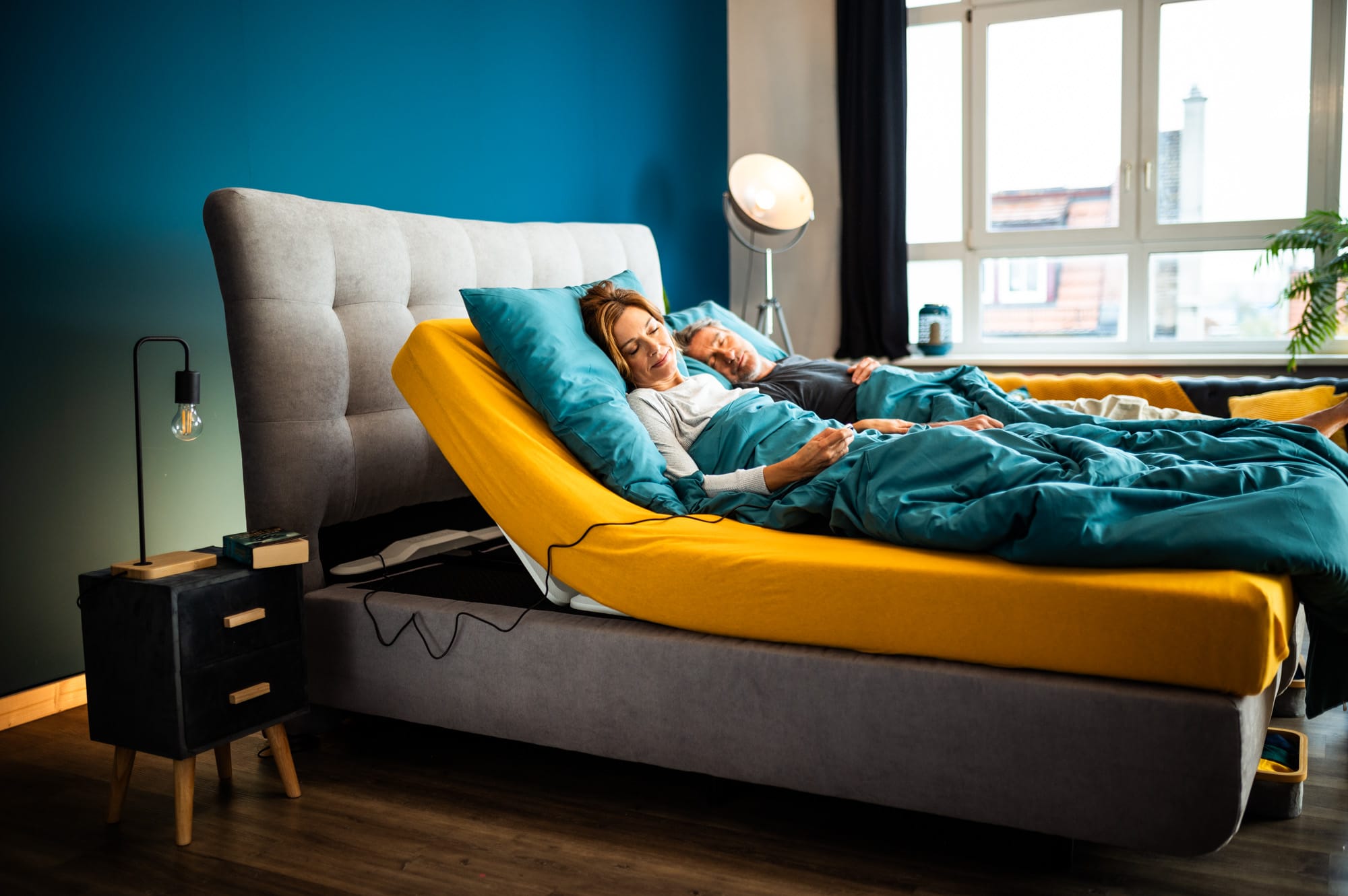 Paar liegt entspannt im Bett mit hochgestelltem Kopfteil durch den elektrischen Lattenrost CosyLift.