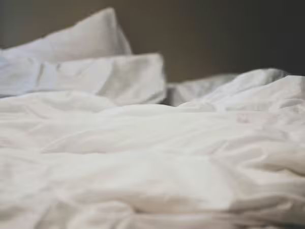 Weiß bezogenes Bett mit Kissen und Decke – Symbol für erholsamen Schlaf und die passende Matratzengröße.