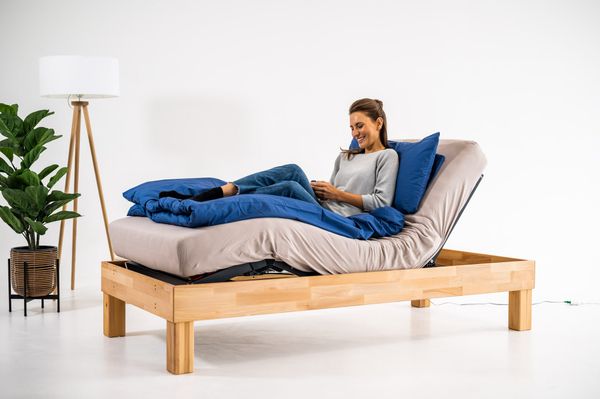 Frau entspannt auf elektrischem Lattenrost Cosy2Go mit hochgestelltem Kopf- und Fußteil im modernen Schlafzimmer