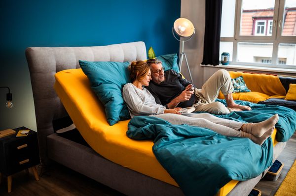Paar entspannt gemeinsam im modernen Kingsize Bett mit verstellbarer Liegefläche