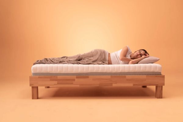 Frau schläft entspannt auf einer Matratze im Seitenschlaf – Symbol für gesunden und erholsamen Schlaf.