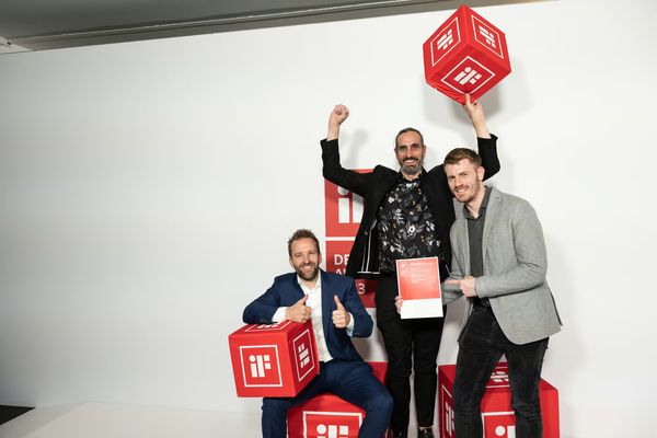 Drei Männer feiern mit Urkunde und roten iF-Design-Award-Würfeln den Gewinn des iF Design Award 2023 für den CosyLift.