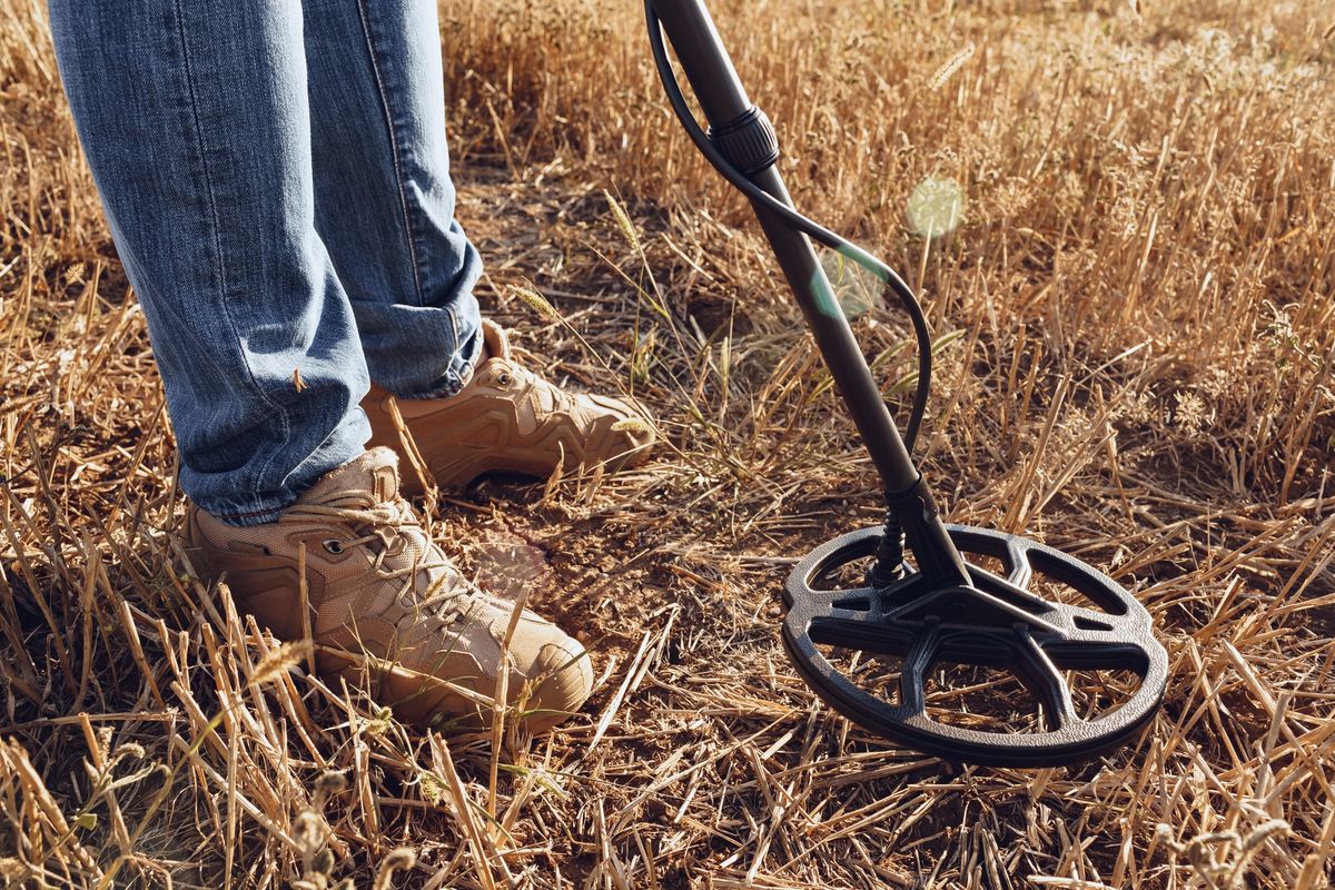 Man with metal detector equipment searching for metal goods in the field