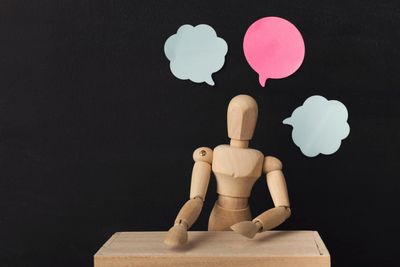 Wooden man mannequin with blank speech bubbles
