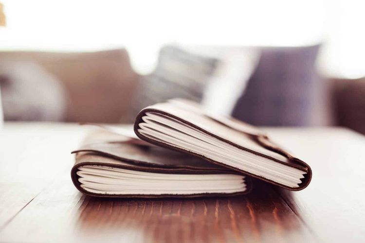 Journals stacked on table.