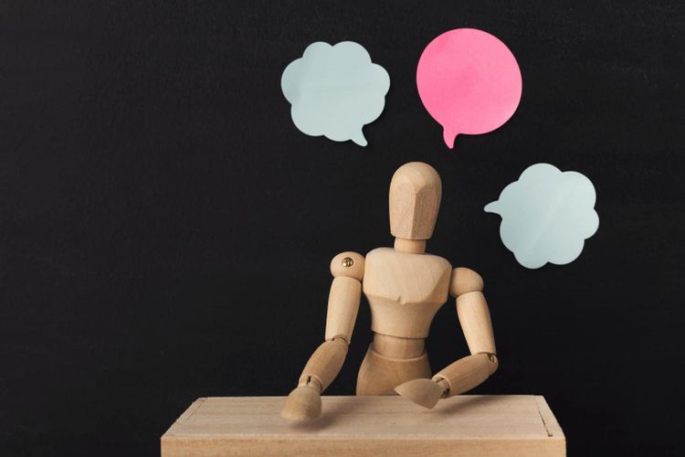 Wooden man mannequin with blank speech bubbles