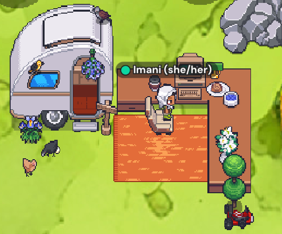 An avatar sitting at a desk, green floor, brown desk, and a gray trailer.