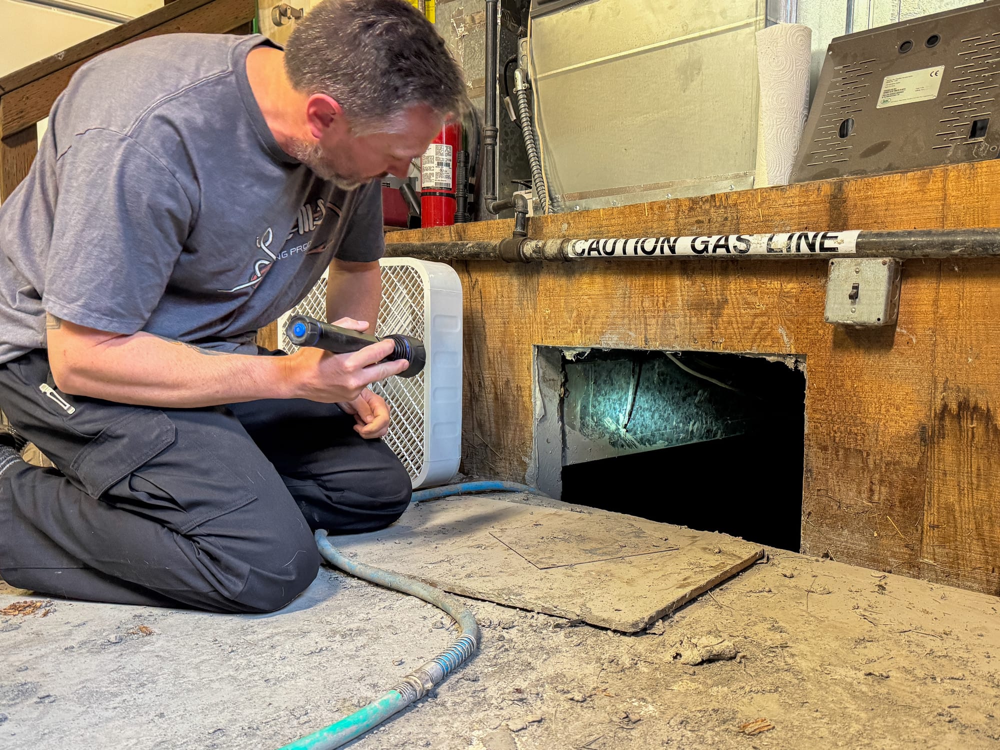 Gavin Ockerman shines a light into a crawl space 