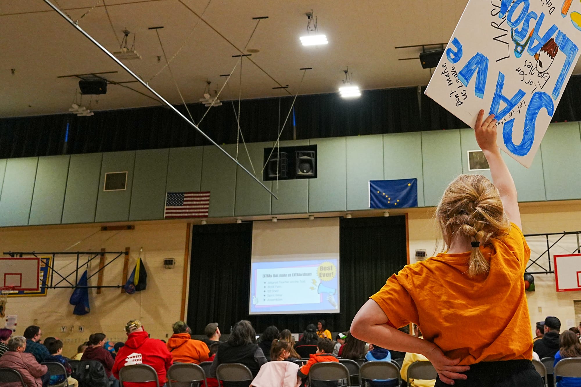 A young Larson Elementary School student holds up a "Save Larson" sign