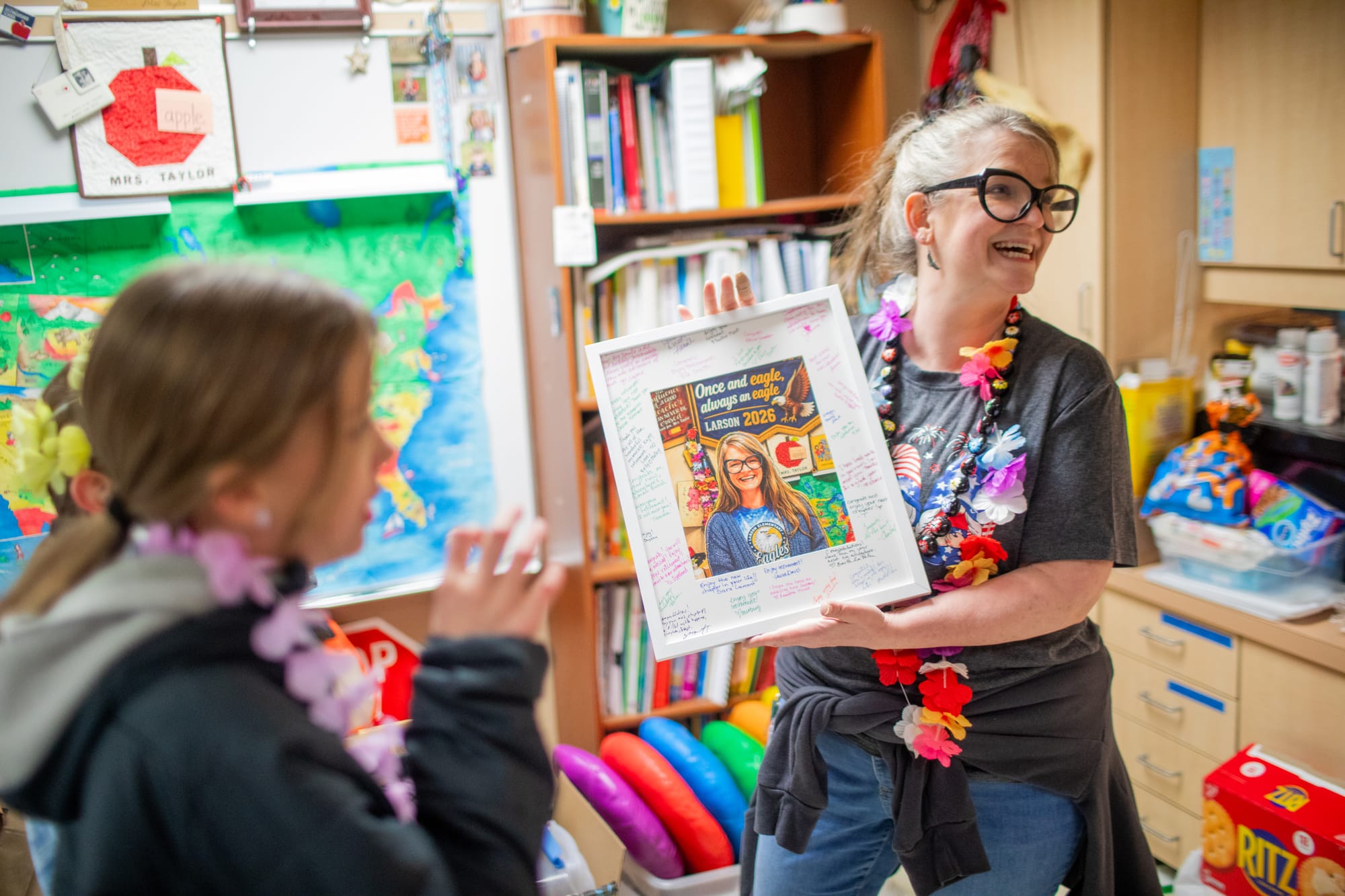 Retiring kindergarten teacher Rebekah Taylor smiles with her staff-signed portrait