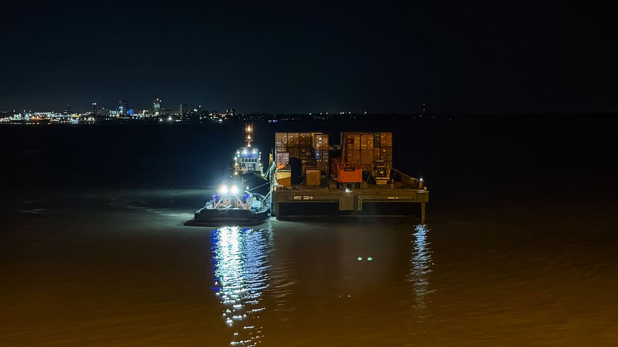A barge of containers holding equipment for an antimony processing plant arrives