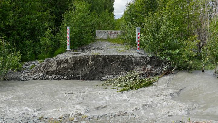 Flood waters flow past an informal levee created by Maud Road on June 23, 2025