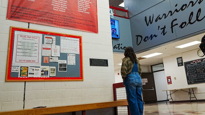 A student reads a land acknowledgment sign in Wasilla High School