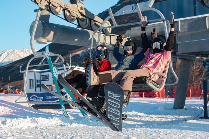 Skiers and a snowboarder ride the Skeetawk lift in Hatcher Pass durning the December, 2025 opening weekend