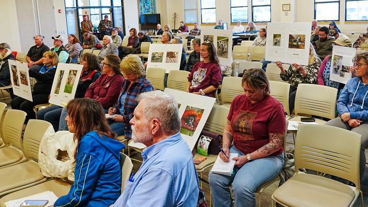Matanuska-Susitna Borough residents hold signs during an April 21, 2026, Borough Assembly meeting