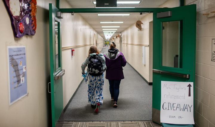 A parent and student walk through Larson Elementary School's empty halls 