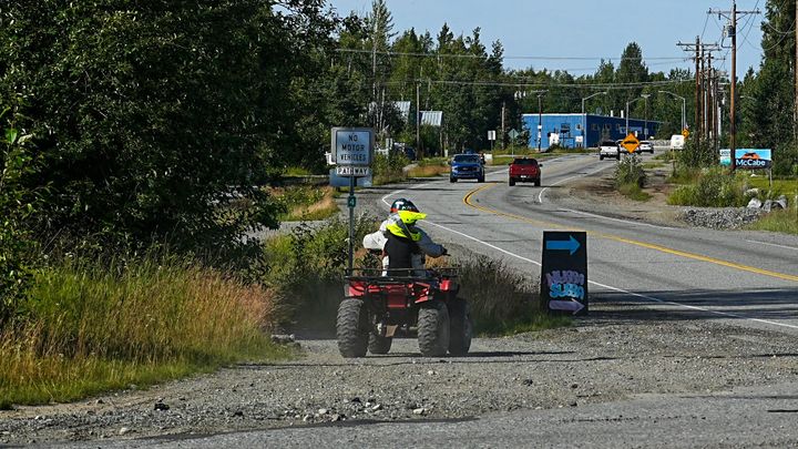 Two individuals on an ATV use a paved pathway 