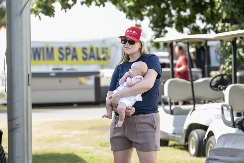 A supporter of Ty Masterson, Republican candidate for Kansas Governor in 2026, holds her baby while watching the Kansas State Fair debate on Sept. 12, 2026. (Dale Grosbach for Citizen Journal)