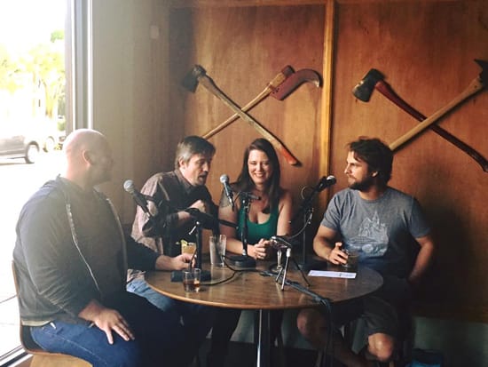 four people sitting at a table with microphones and beer