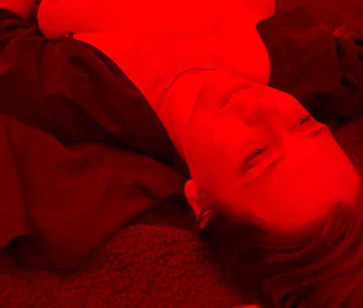 A woman with an open shirt laying on a bed