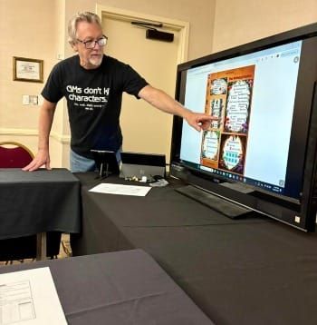 A man is pointing to a tv display showing a menu system for a role-playing game
