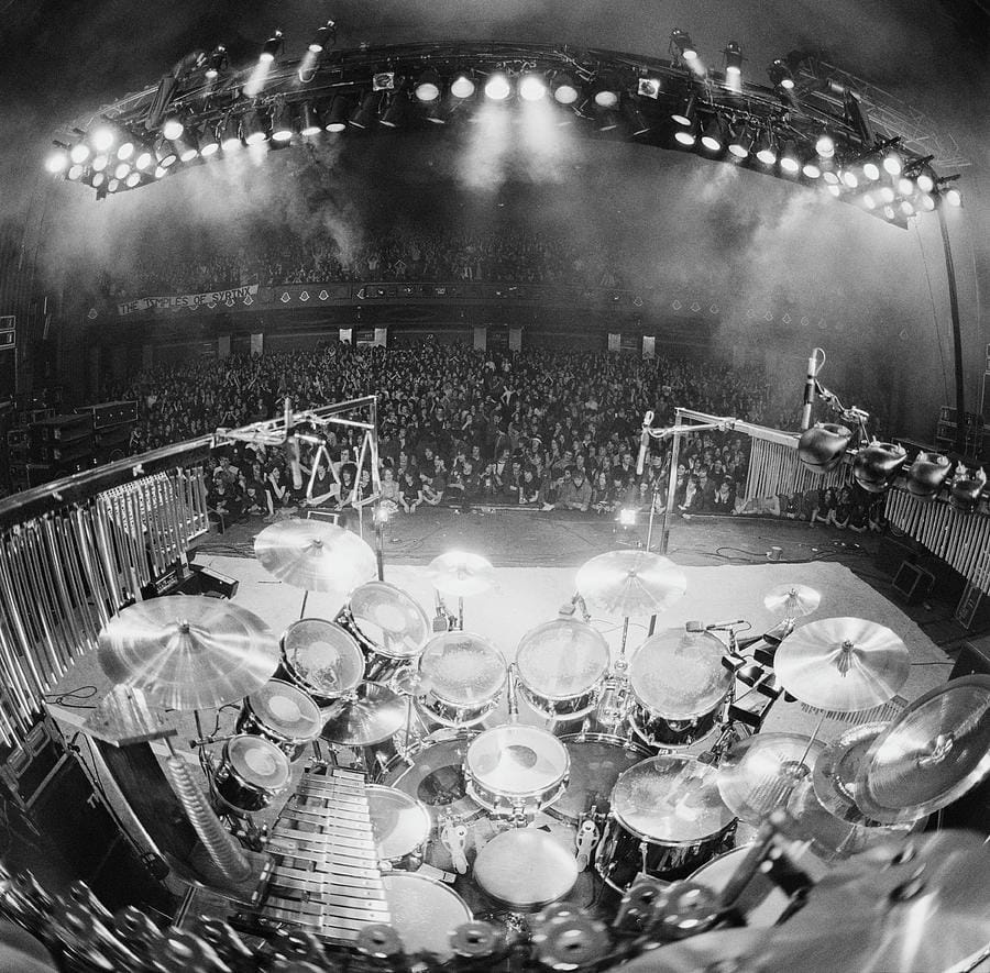 Rush in concert — Fin Costello. Stage light, deep shadow, and grain doing the work.