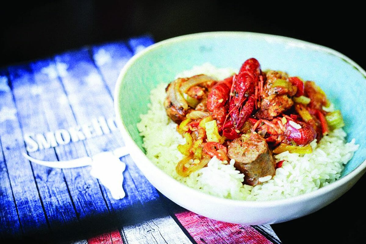 Sur un menu des restaurants Smokehouse, une assette creuse avec du riz et du Jambalaya par dessus, écrevisses et saucisses.