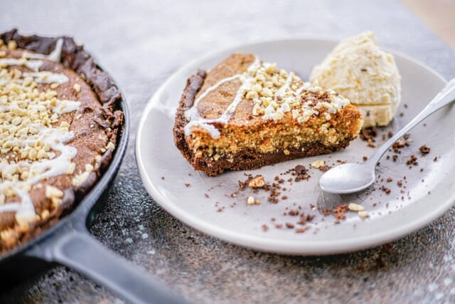 assiette à dessert avec une portion de tarte au beurre de cacahuète et une boule de glace vanille.